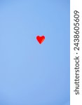 Red heart balloons over blue sky. Love, valentines day, romantic, wadding or birthday background. a red balloon in the shape of a heart is flying away into the blue sky. Letting go of my heart