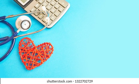 Red Heart And Calculator With Stethoscope Isolated On Blue Background. Tax Offset Concept. Medical Expense Deductions And Tax Breaks. Affordable Care Act. High Cost Health Care