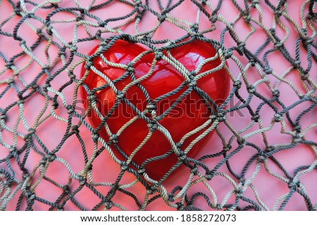 red heart covered with mesh. concept of rejection of love, prohibition of free expression of emotions, concept of constraint , oppression
