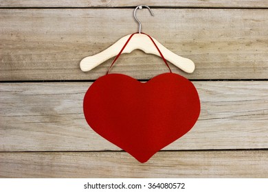 Red heart hanging on hanger with antique rustic wood background; Valentine's Day and love concept - Powered by Shutterstock