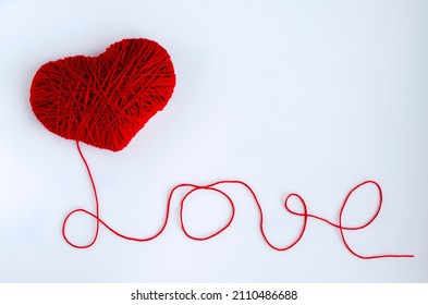 A red heart and the inscription LOVE from threads. The concept of creativity and hobbies. Valentine's Day holiday.