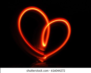 Red heart light glowing graffiti made on dark black background - Powered by Shutterstock