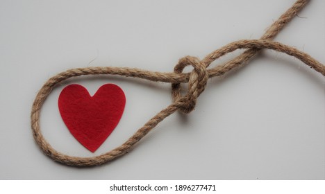 Red heart in a loop of rope cord. Feelings trap. Emotions. Toxic relations. Affection. Dependence. Abuse. Unhealthy relationship. Dysfunctional love. Manipulation.  - 10 January 2021, Montreal, Canada