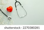Red heart love shape hand exercise ball with stethoscope on blue background with flowers. Health care, organ donation, love and family insurance concept, world heart day. Flat lay, copy space
