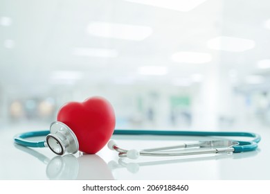 Red Heart Love Shape Hand Exercise Ball With Doctor Physician's Stethoscope On Hospital Background: Hospital Life Insurance Concept: World Heart Health Day. Doctor Day, World Hypertension Day