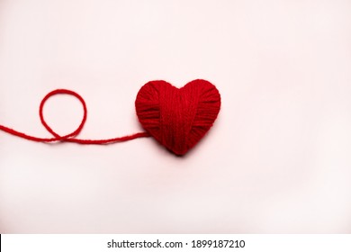 Red heart made of wool on a white background