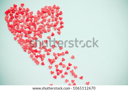 Red heart on a light background. The heart is crumbling, falling apart. Disappointment in love, unrequited feelings, the soul is torn to shreds. Copy space, top view.