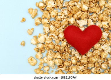 Red heart on the popcorn on the blue background. Concept: fast food for Valentine's Day. Selective focus. Love of movies and popcorn.The view from the top