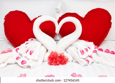 Red heart pillows and two towel swans shaped on the bed,Honey moon bed