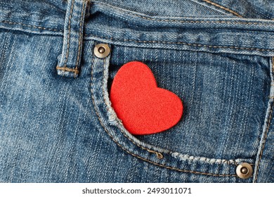 A red heart in the pocket of a blue jeans trouser in a close up view - Powered by Shutterstock