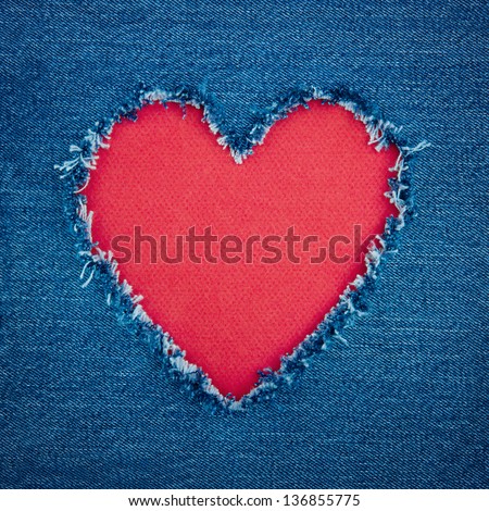 Red heart shape for copy space torn from blue denim jeans fabric, romantic love concept background