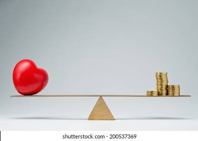 Red Heart Shape And Money Coins Stack Balancing On A Seesaw