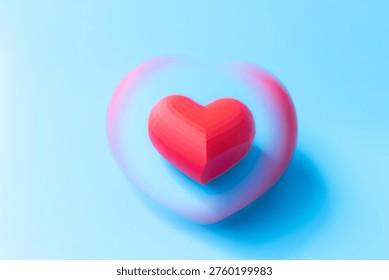 Red heart shape with a soft blurred outline against a light blue background, representing love and affection in a clean and minimalist style