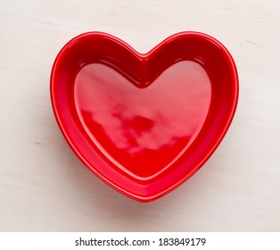  Red heart shaped bowl on white wooden surface