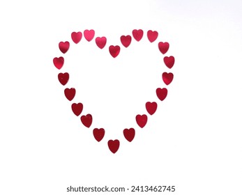 Red, heart shaped sequins arranged in the shape of a heart on the white background.