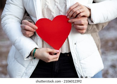 Red heart symbol of all lovers is held together in hands of couple in love. Valentine's Day holiday. Concept of dating. Declaration of love. Romantic date in woods. Lovers' Holiday. Love emotions. - Shutterstock ID 2106012392