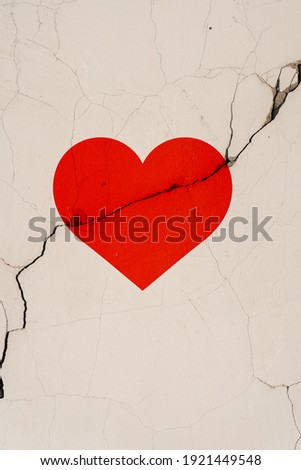 The red heart symbol is located on a crack in the wall. Vertical foto