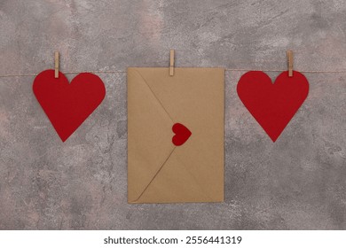 Red hearts and an envelope hang on a string on a textured gray-pink background. Decoration for Valentine's Day. - Powered by Shutterstock