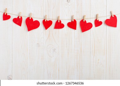 Red hearts on rope with clothespins, on a white wooden background. Place for text, copy space.