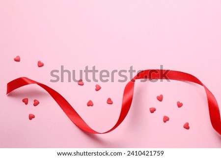 Red hearts with ribbon on color background, top view