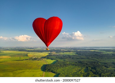 Red heart-shaped balloon with people over green fields and forests. - Powered by Shutterstock