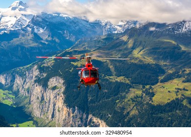 Red helicopter flying in the alpine mountains of Switzerland - Powered by Shutterstock