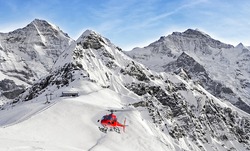Red Helicopter Flying Near Swiss Ski Resort Near Jungfrau Mountain In Winter