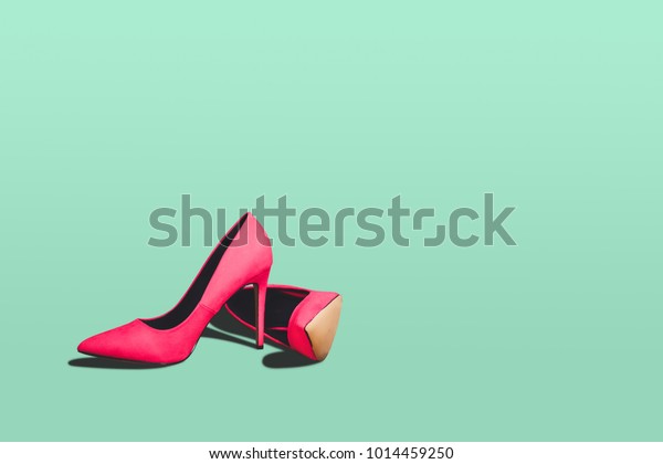 Red high heels isolated on a bright green pastel\
background. Fashion concept, catwalk. A modern and fashionable shoe\
store.