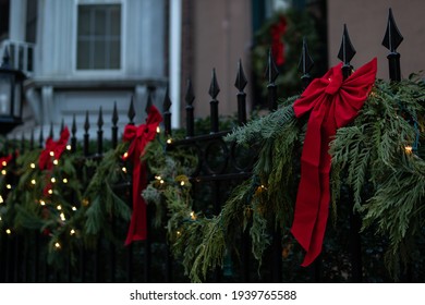 Red Holiday Christmas Bows And Lights With Pine Branch Decorations On A Fence In New York City