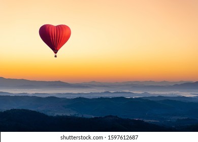 Red hot air balloon in the shape of a heart flying over the mountain - Shutterstock ID 1597612687