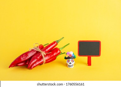 Red hot chili pepper and Catrina La Calavera Garbancera , Dapper Skeleton, Elegant Skull and small blackboard on a yellow background