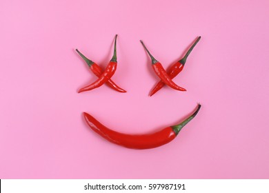Red hot chili pepper on pink,  funny face made of chili