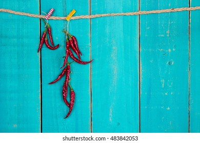 Red hot chili peppers hanging from rope by antique rustic teal blue wood background - Powered by Shutterstock