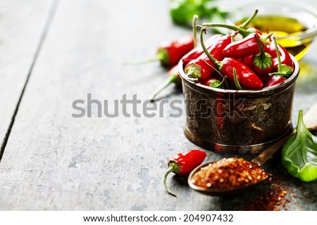 Red Hot Chili Peppers with herbs and spices over wooden background - cooking or spicy food concept