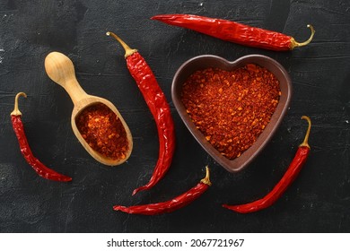 Red Hot Chili Peppers Powder In Heart Shaped Bowl On Black Stone Table. Love Concept. Top View Flat Lay With Copy Space