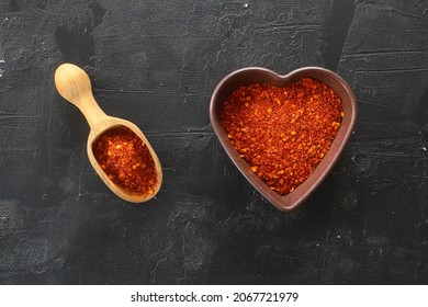 Red Hot Chili Peppers Powder In Heart Shaped Bowl On Black Stone Table. Love Concept. Top View Flat Lay With Copy Space