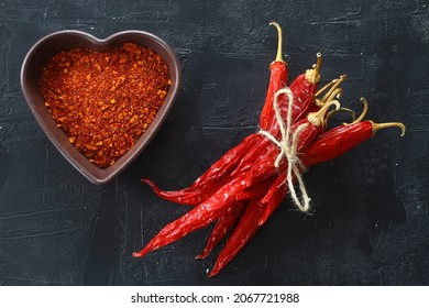 Red Hot Chili Peppers Powder In Heart Shaped Bowl On Black Stone Table. Love Concept. Top View Flat Lay With Copy Space