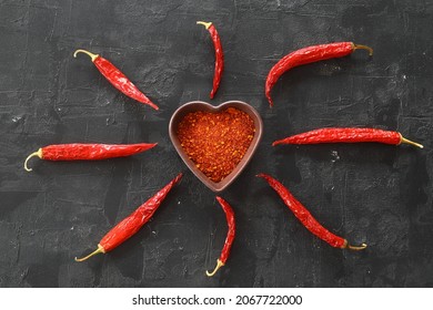 Red Hot Chili Peppers Powder In Heart Shaped Bowl On Black Stone Table. Love Concept. Top View Flat Lay With Copy Space