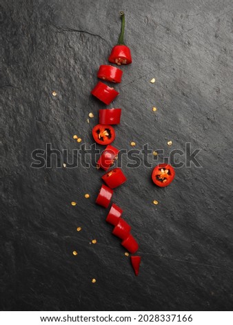 Red hot chilli pepper on dark black rough slate stone surface background