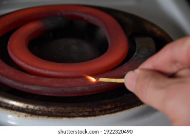 Red Hot, Glowing Element. Electric Stove With A Spiral. Image Of An Electric Stove Heating Element. The Hand Brings The Match To The Knee Coil, And The Sulfur Ignites. Burning Match And Electric Stove