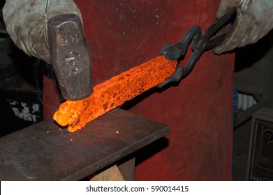 Red hot from the intense heat of a forge, the blacksmith skillfully works the glowing metal to contour it into a handmade knife. - Powered by Shutterstock