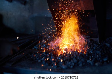 Red Hot Metal In Burning Fire Preparing For Forging Process At Workshop. Sparks Flying Around. Traditional Blacksmith Manufacture.