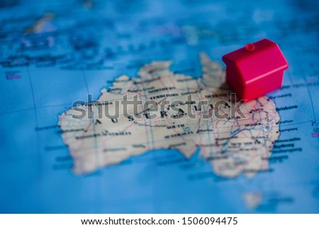Red house model on Australia part of world map. Buying of real estate in / migration to Australia concept.