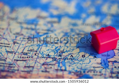 Red house model on Canada part of world map. Real estate buying in/ migration to Canada concept.