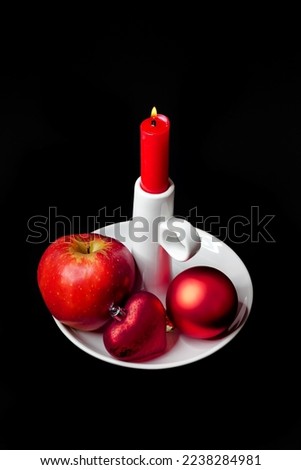 Red household candle with a white porcelain stand and Christmas decorations