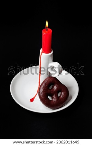 Red household candle with a white porcelain stand and Christmas decorations