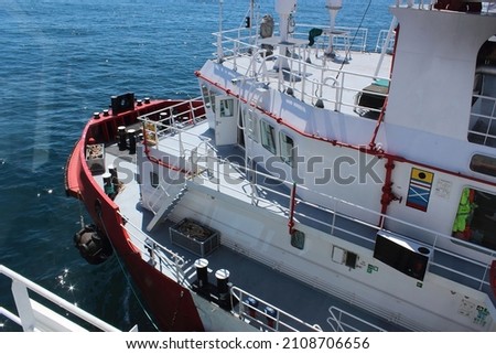 Red hulled standby safety vessel in ship to ship operation. It is used to refuel and resupply seismic survey vessels during oil and gas exploration.