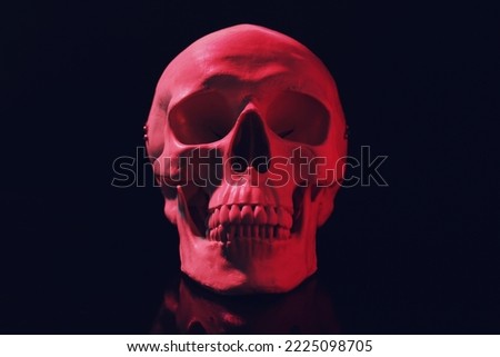 Red human skull with teeth on black background