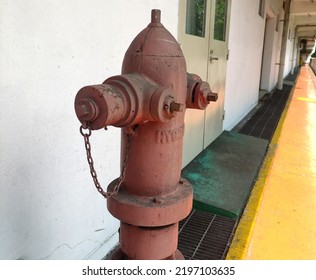 A Red Hydrant Standing Tall In The Hall Of The Building.  Fire Extinguisher Always On Standby.  Savior In Times Of Fire Disaster