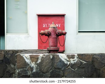 The red hydrant is in the yard between the stone walls